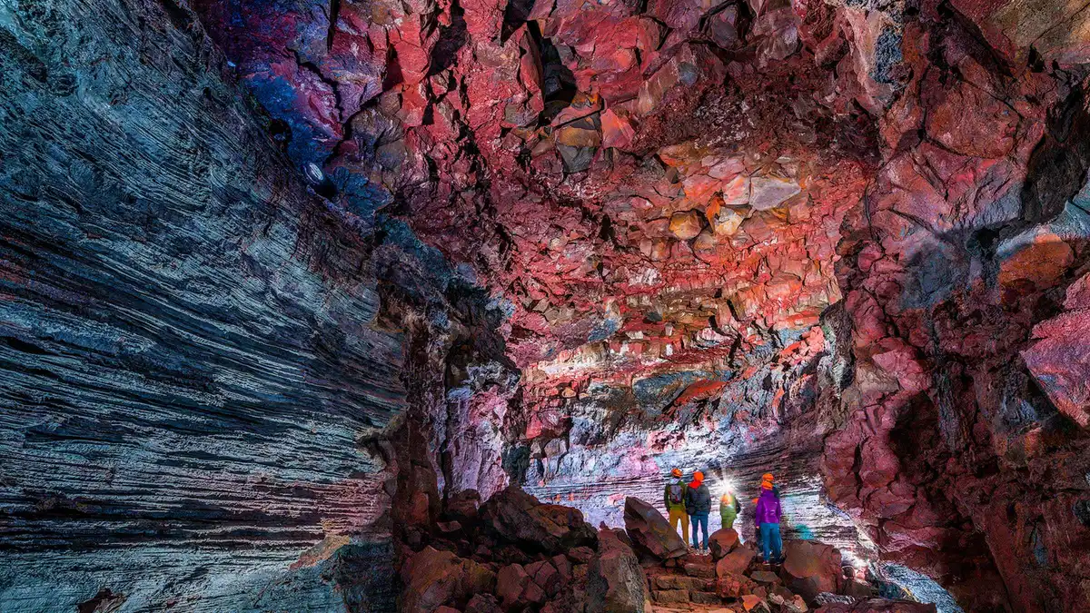Caver with a head torch beyond the walkway on the Lava Falls Adventure Raufarhólshellir lava tunnel tour, Þrengsli, Iceland